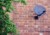 A picture of a satellite dish attached to a red brick wall